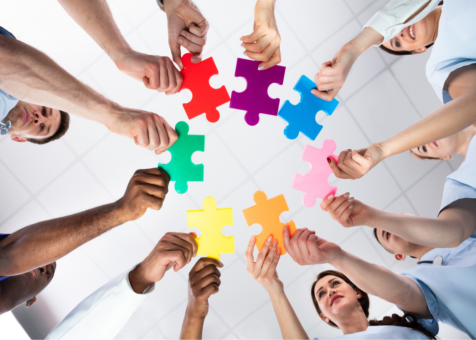 A diverse group of healthcare professionals collaboratively holding up colorful puzzle pieces, symbolizing teamwork and unity in the medical field.
