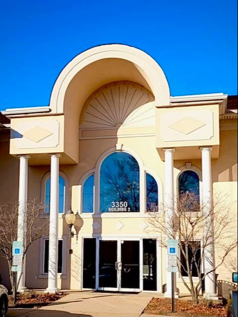 The grand entrance of Building 2 at 3350, displaying a prominent arched doorway and tall columns under a blue sky.