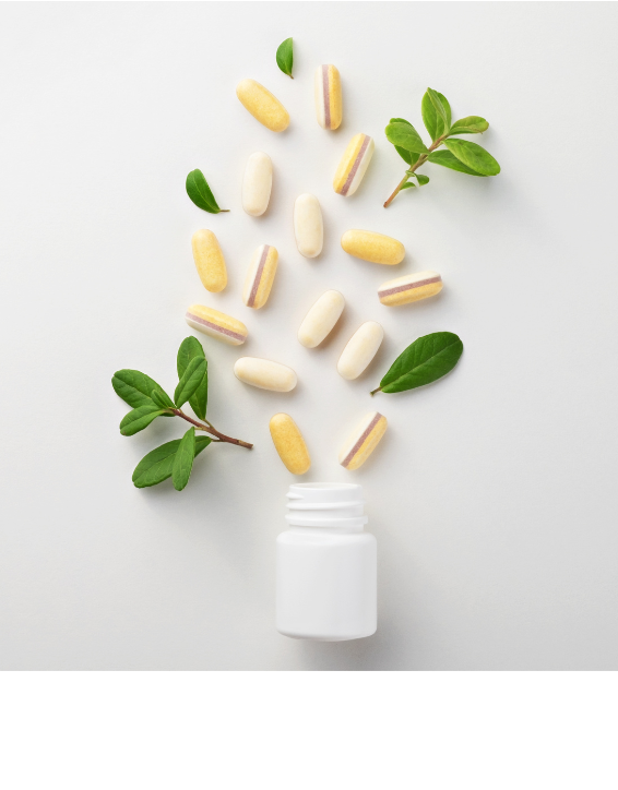 Supplement capsules and green leaves spilling from an open bottle